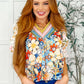Model wearing a floral V-neck blouse with vibrant colors and ruffled sleeves, styled with a chic outfit.
