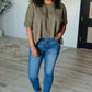 Model wearing Less Than Stressed Asymmetrical Distressed Top with jeans, showcasing a stylish casual look.