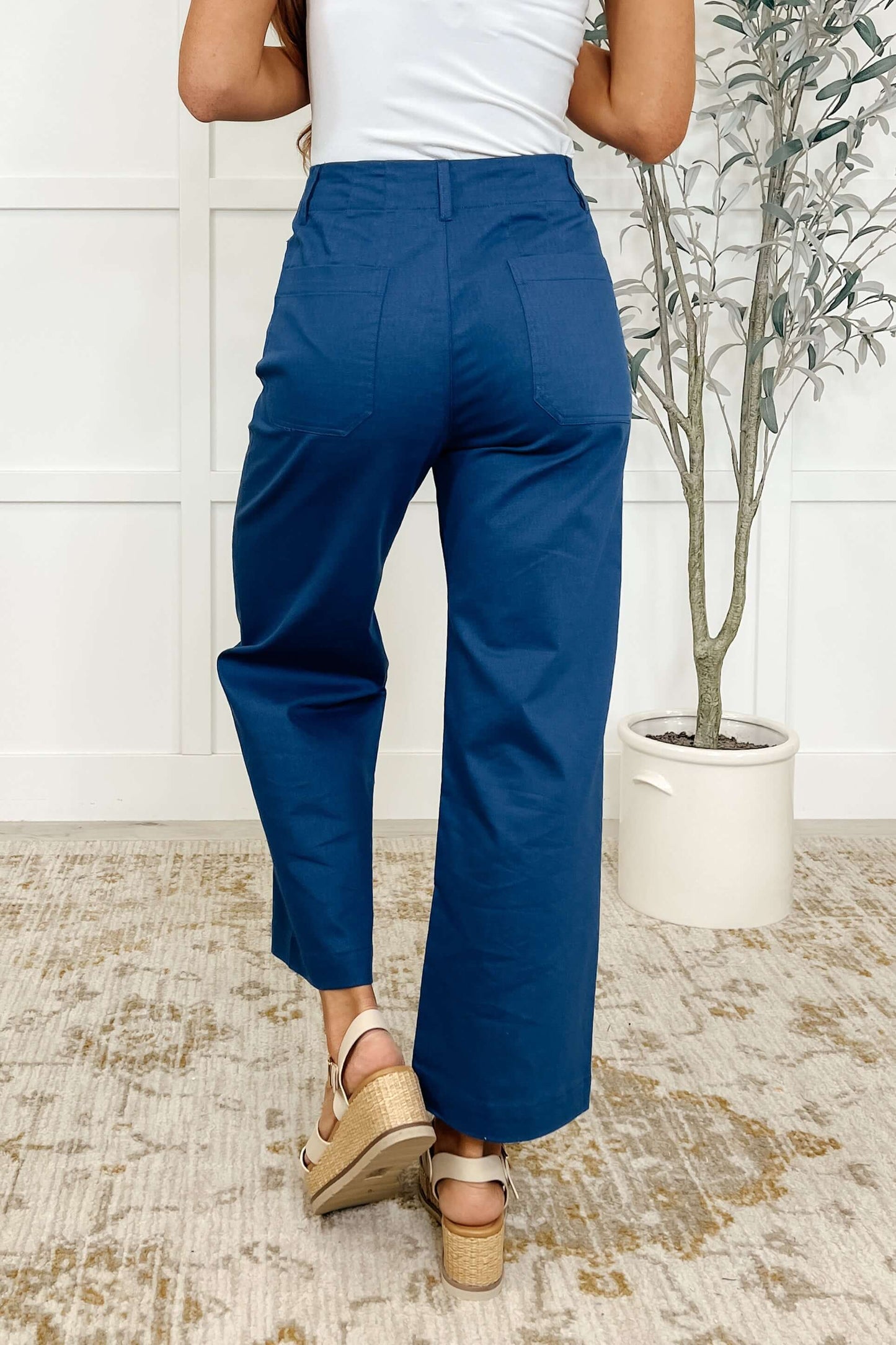 Back view of a woman wearing royal blue Little Strolls straight leg trousers with a cropped wide leg style.