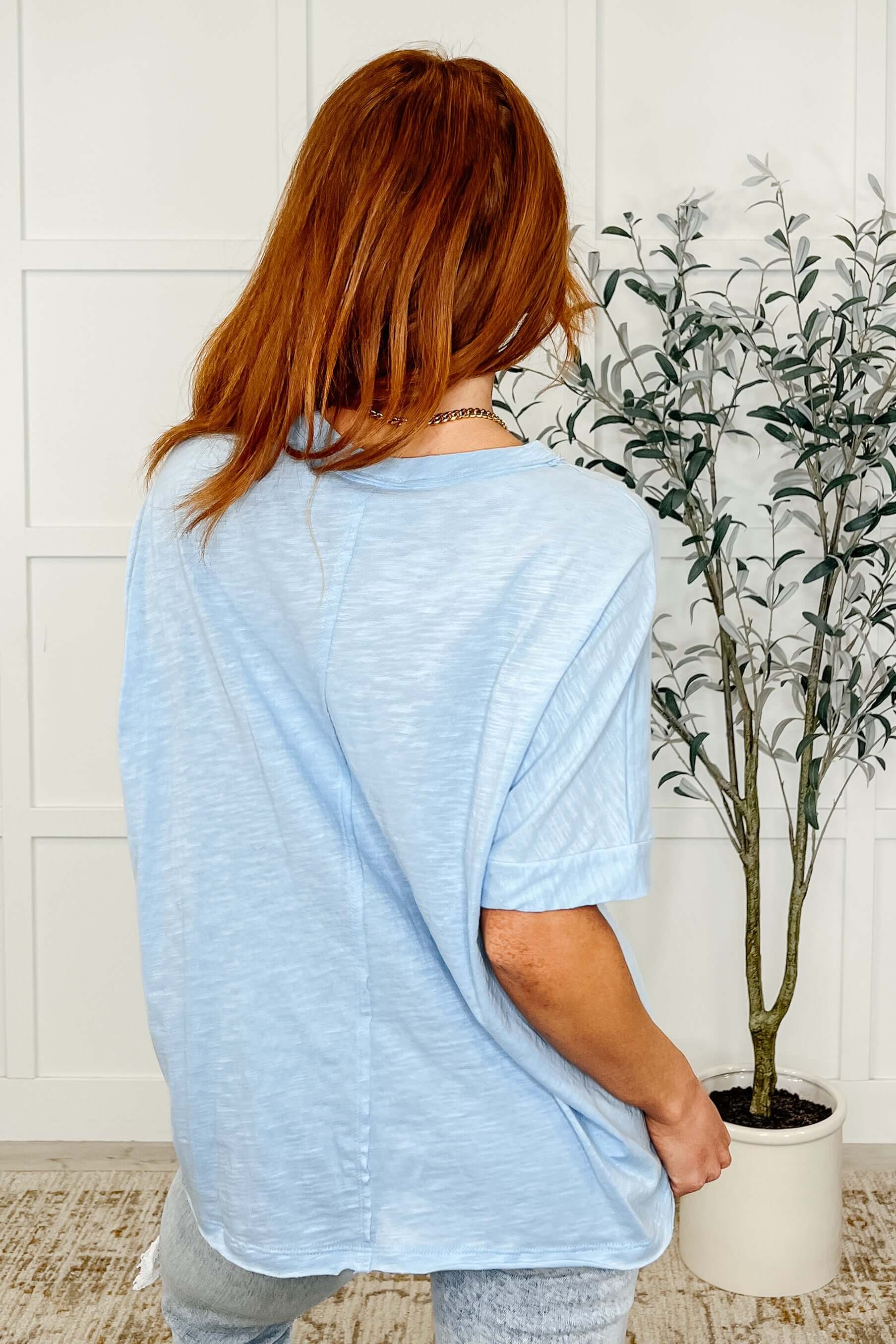 Woman showcasing the back of the Layback Relaxed Basic Tee in Light Blue, featuring a slouchy fit and relaxed style.