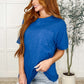 Woman wearing The Layback Relaxed Basic Tee in royal blue, styled with denim shorts in a cozy indoor setting.